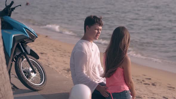 Man and Girl Sit Together Chat and Hug Against Ocean