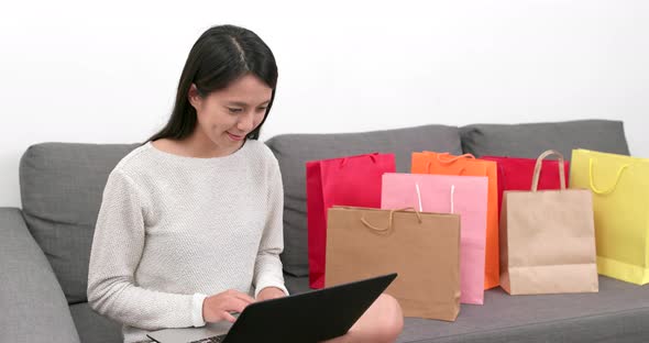 Shopping woman use of notebook computer with lots shopping bag at home