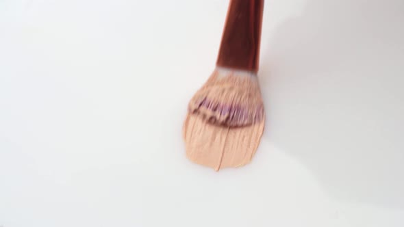 Beige Smear of Makeup Foundation Cream with a Brush on White Background