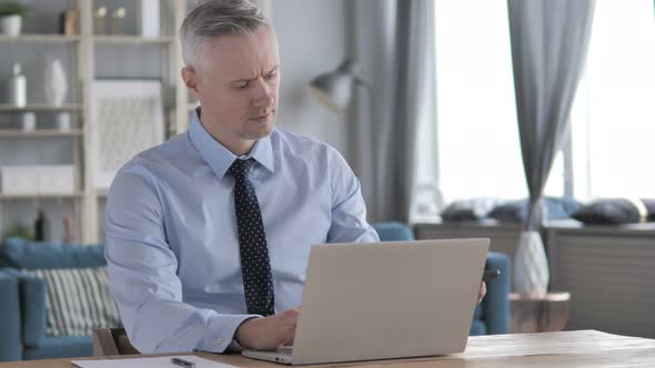 Gray Hair Businessman Attending Phone Call While Working on Laptop