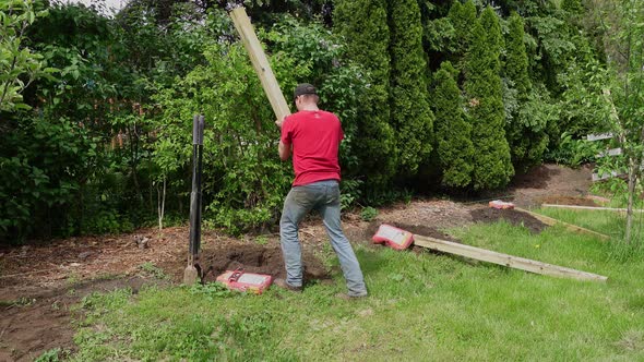 Setting wooden fence pole down and leveling it with tool, static view