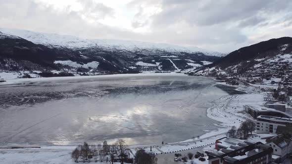 Aerial moving over Voss and showing frozen Vangsvatnet lake close to hotels and road