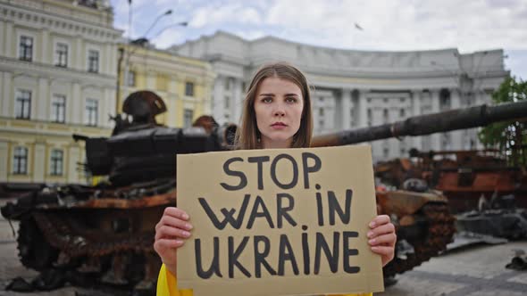 Woman Covered with Flag Lifts Poster Standing Against Tank