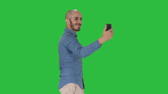 Happy smiling handsome young man making selfie while walking