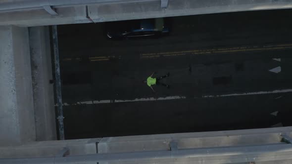 AERIAL: Young Man Laying on Street Slow Birds Eye View Flight Over Downtown Los Angeles California