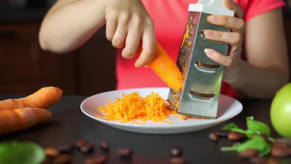 Young Woman Rubbing Carrots on a Grater