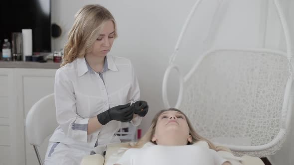 Portrait of Young Attractive Smiling Beautician Doctor with Syringe in Hand Posing to Camera