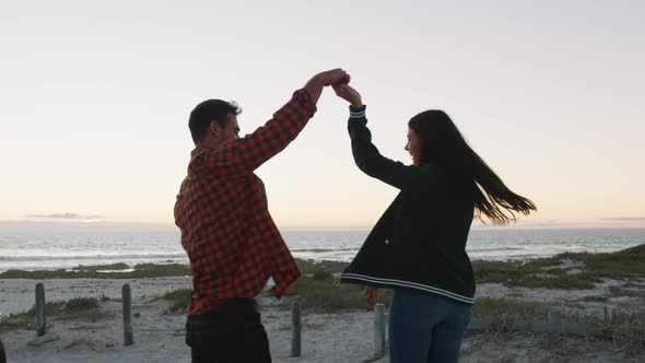 Happy caucasian couple dancing on the beach by the sea