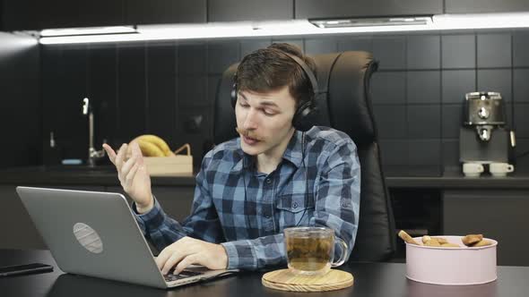 Man in headphones making call video conference at home