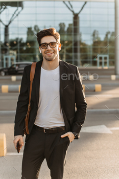 Happy man in black jacket, pants and white t-shirt smiles sincerely. Handsome guy in eyeglasses hol / Photodune, Misc