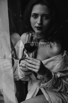 Beautiful woman looking into camera and holding wine glass. Black and white portrait of charming la / Photodune, Misc