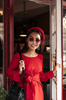 Young brunette Asian woman in red beret, bright stylish dress and colorful sunglasses smiles sincer / Photodune, Misc