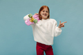 Lovely little girl with red hair in stylish pants and trendy white sweater pointing to place for te - PhotoDune Item for Sale