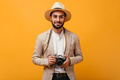 Smiling man in beige outfit holding retro camera on orange background. - PhotoDune Item for Sale