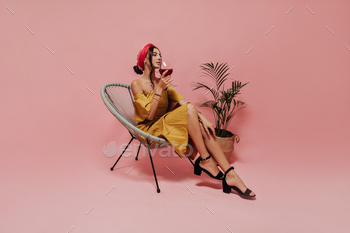 Woman with cool hairstyle in red bandana, midi dress and black heels sitting and enjoying glass of / Photodune, Misc