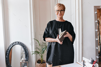 Beautiful lady in oversized dress looks into camera and holds notebook / Photodune, Misc