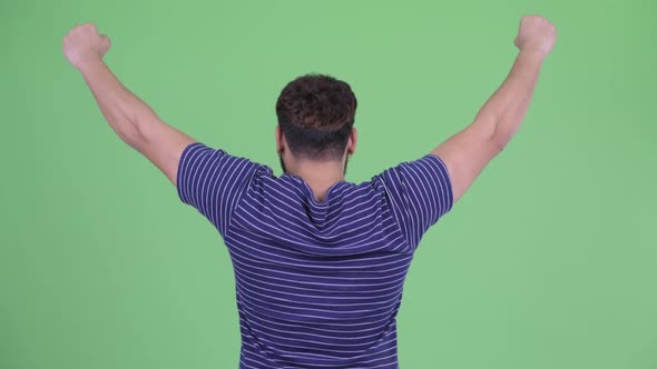 Rear View of Happy Young Overweight Bearded Indian Man with Fists Raised