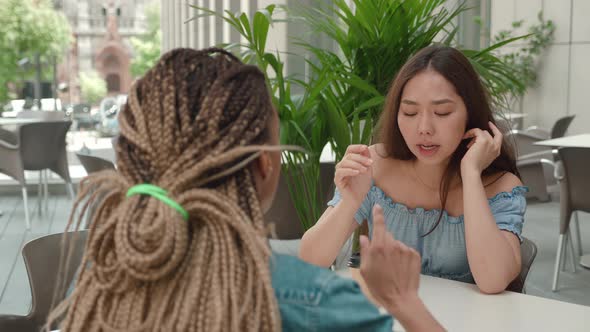 Two Female Friends Talking Over Coffee Outside a Coffee Shop