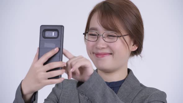 Face of Young Happy Asian Businesswoman Using Phone