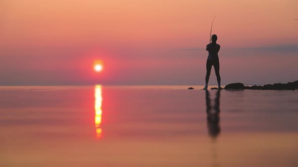 Woman Fishing on Fishing Rod Spinning at Sunset Background