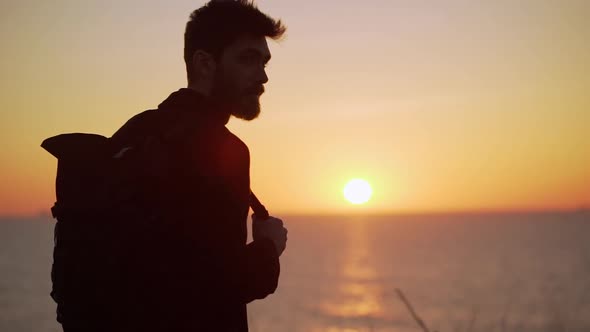 Attractive Man Standing Against the Raising Sun Smiling Looking to the Side Backlighting Slow Motion