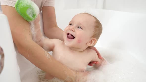 Funny Baby Boy with Soap Foam on Head Playing in Bathroom with Toy Boats and Ships