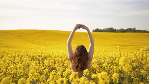 Young Naturist Woman Enjoys Spring in Rapeseed Field