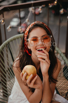 Healthy Lady in orange sunglasses holds apple and smiles. Lovely girl with beautiful smile in red b / Photodune, Misc