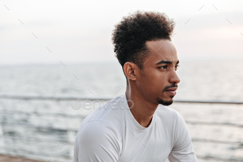 Portrait of curly brunette dark-skinned thoughtful man in white sport long-sleeved t-short looking / Photodune, Misc