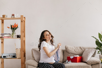 Cheerful pregnant woman holds clothes of her baby. Portrait of happy brunette mother smiling and si / Photodune, Misc