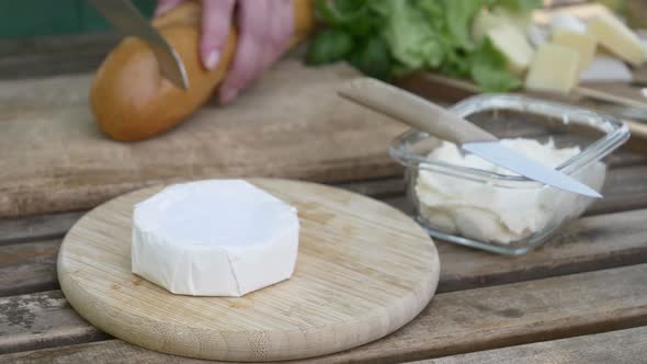 Stylish woman make a snack with bread and cheese on a table in outdoor