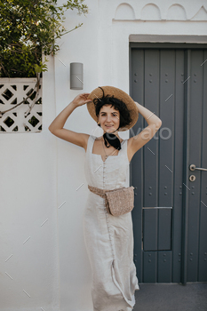 Brown-eyed brunette woman in white dress puts on boater outside. Cheerful young lady in hat and sum / Photodune, Misc