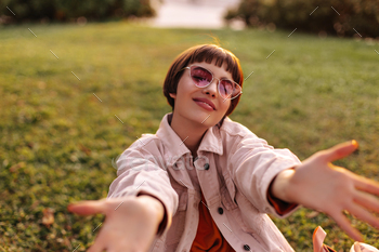 Short-haired woman wants hugs. Stylish charming girl in pink denim jacket and sunglasses smiles and / Photodune, Misc