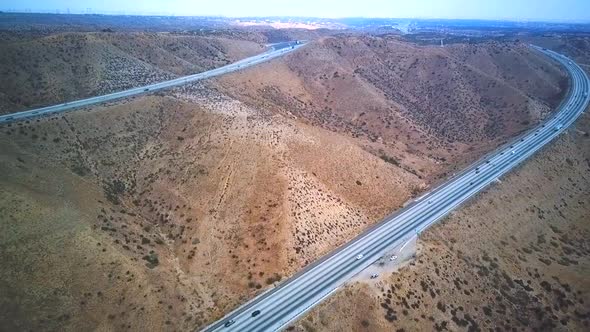 Aerial view of highway and cars during a road trip in dry and rugged terrain