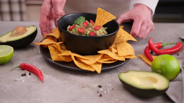 Woman Puts Nachos Chips and Freshly Made Guacamole on the Table