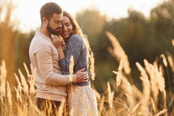 Beautiful agricultural field. Cheerful lovely young couple having a rest outdoors together / Photodune, Misc