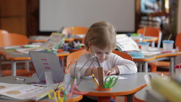 Girl Drawing at the Table in Classroom. Education. Child Sitting at a Desk