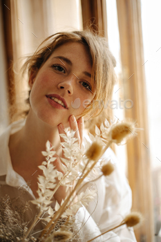 Beautiful woman with freckles looks into camera. Parisian lady in white blouse gently touches skin / Photodune, Misc
