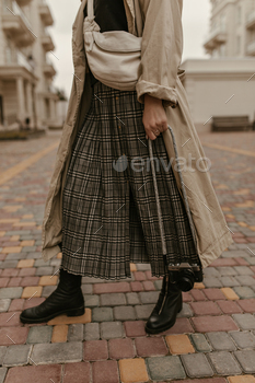 Photo of woman in midi grey checkered skirt, black top and beige trench coat poses with stylish han / Photodune, Misc