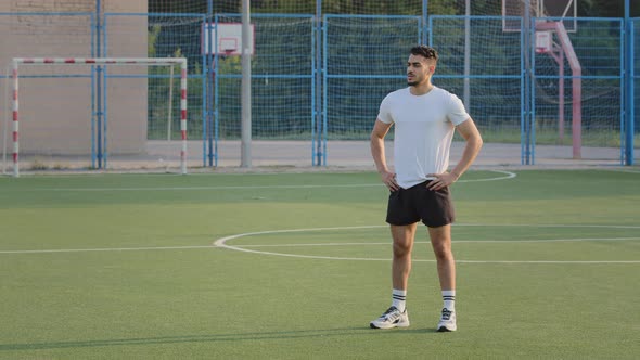 Young Experienced Coach Indian Guy in Summer Sportswear Standing on Football Field of School Stadium