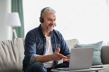 Cheerful mature businessman having video conference from home / Photodune, Misc