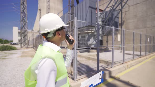 Engineer walking in factory while talking by walkie-talkie.