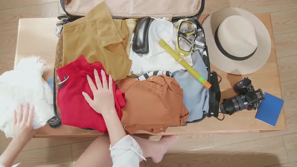 Woman Traveller Packing Clothes In A Suitcase For A New Journey. Luggage For Holidays. Top View