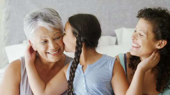 Daughter kissing grandmother on cheeks in bed room 4k