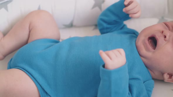 Upset Newborn Child Cries Bothering Legs in Sleeping Cocoon