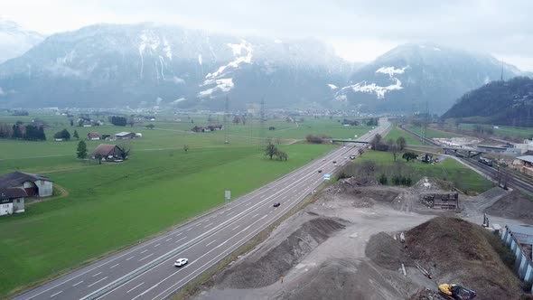 Highway construction site to upgrade the route leads through green meadows with a mountain range in