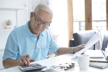 ncept – senior man with calculator and bills counting money at home. Senior man calculating taxes at home