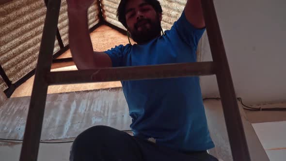 View Of A Man Climbing On A Steel Ladder Inside An Unfinished Building