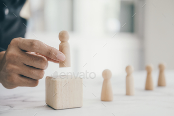 an resource. Businessman hand choose wooden human doll from many cadidate and different.