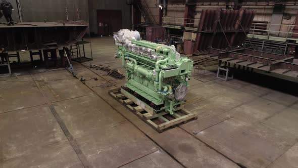 Colorful Wrapped Engine on Floor and Worker on Repaired Ship